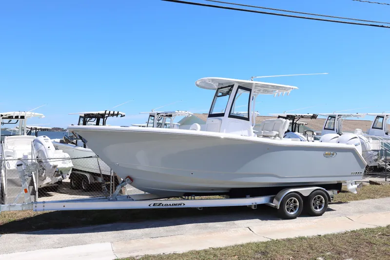 Slide: The Image of 2026 Sea Hunt Gamefish 25 boat on trailer, parked outdoors under clear blue sky. - 24