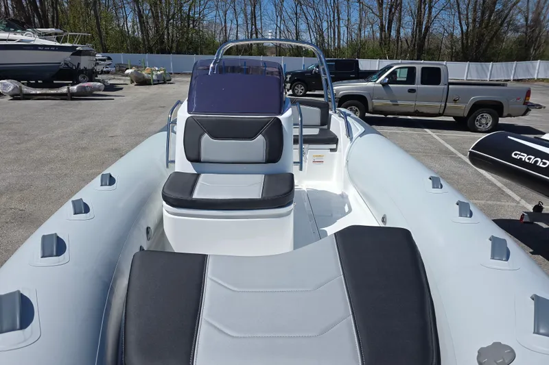 Slide: The Image of 2026 Grand Inflatables G500 boat with sleek seating, parked in a lot with vehicles. - 6
