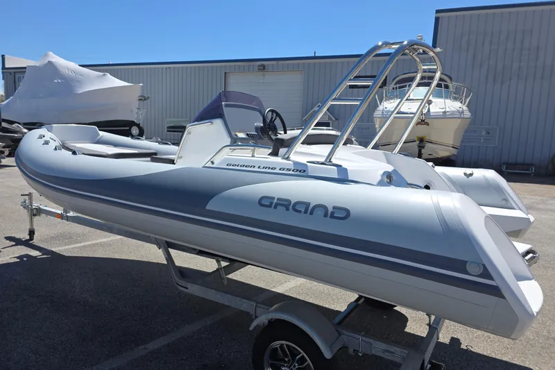 Slide: The Image of 2026 Grand Inflatables G500 boat on trailer, parked outdoors under clear blue sky. - 3