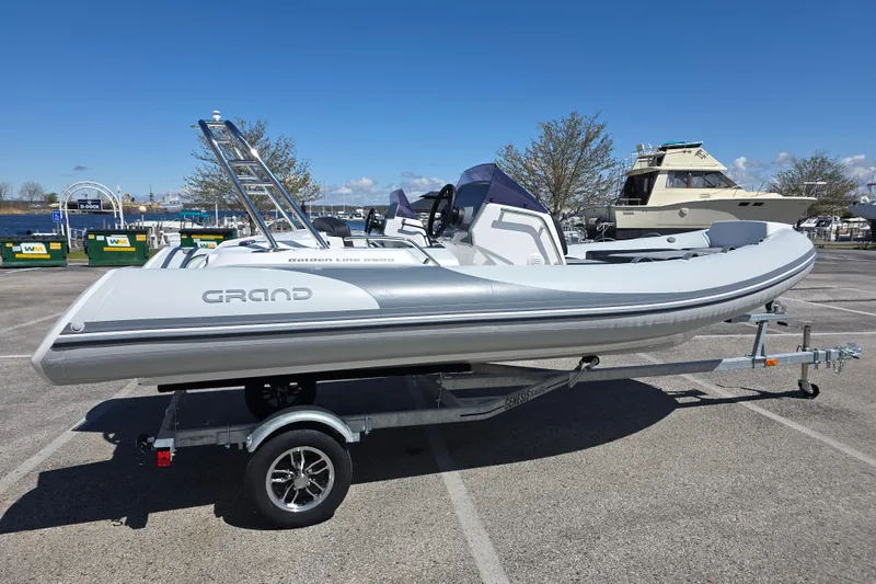 Slide: The Image of 2026 Grand Inflatables G500 boat on trailer in marina parking lot. - 2