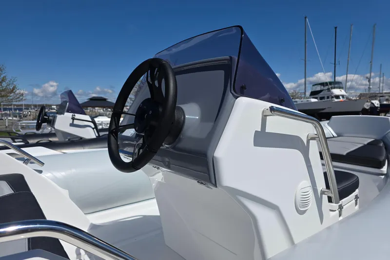 Slide: The Image of 2026 Grand Inflatables G500 boat with sleek console and steering wheel, docked at marina. - 4