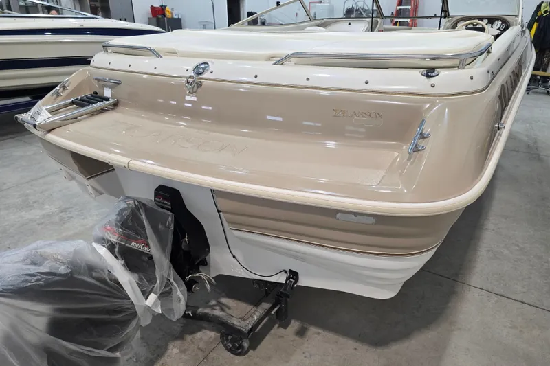 Slide: The Image of 1996 Larson LXi 218 boat in a showroom, showcasing its sleek design and outboard motor. - 11