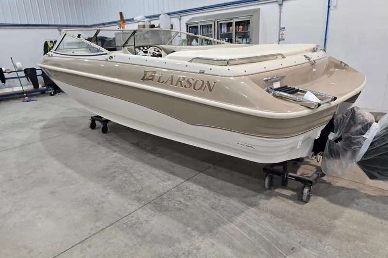 Slide: The Image of 1996 Larson LXi 218 boat in a garage, beige and white exterior, on a wheeled stand. - 13