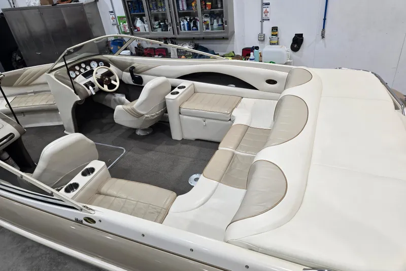 Slide: The Image of 1996 Larson LXi 218 boat interior with beige seating and dashboard in a garage setting. - 37