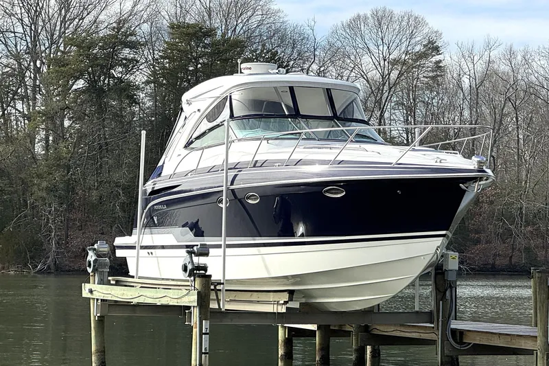 Slide: The Image of 2016 Formula 34 Performance Cruiser on a lift by a wooded shoreline. - 2