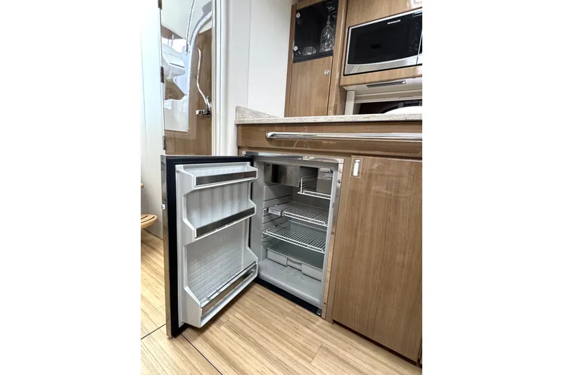Slide: The Image of 2016 Formula 34 Performance Cruiser interior with open fridge and wooden cabinetry. - 27