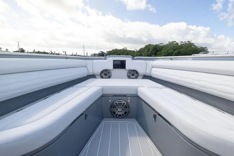 Slide: The Image of 2026 Cigarette 42' Auroris boat interior with white seating and speakers under a cloudy sky. - 8