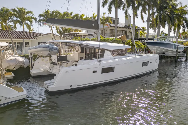 Slide: The Image of 2019 Lagoon 42 catamaran docked by palm trees, reflecting on calm water. - 104