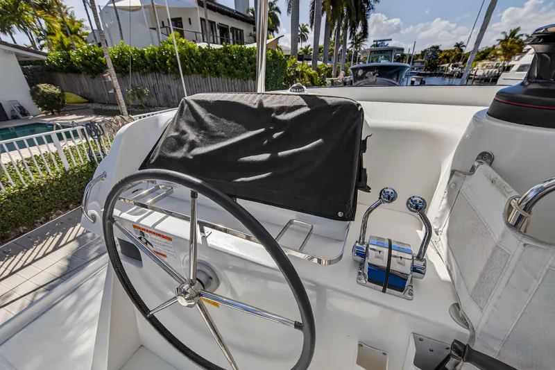 Slide: The Image of Helm of 2019 Lagoon 42 catamaran with steering wheel and controls, docked near palm trees. - 11