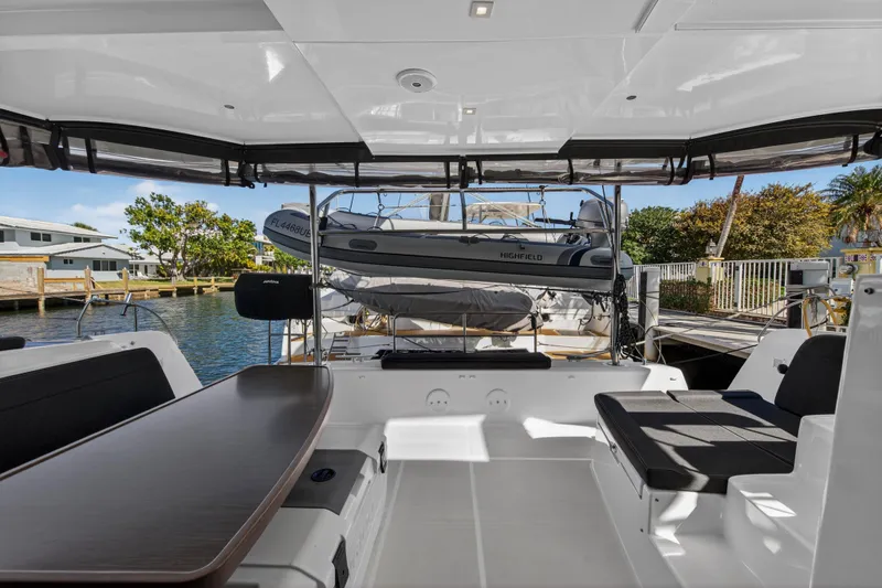 Slide: The Image of 2019 Lagoon 42 yacht interior with seating and table, docked by waterfront homes. - 15