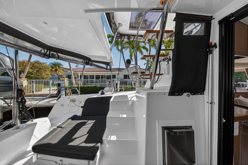 Slide: The Image of 2019 Lagoon 42 catamaran cockpit with seating, stairs, and tropical marina view. - 20