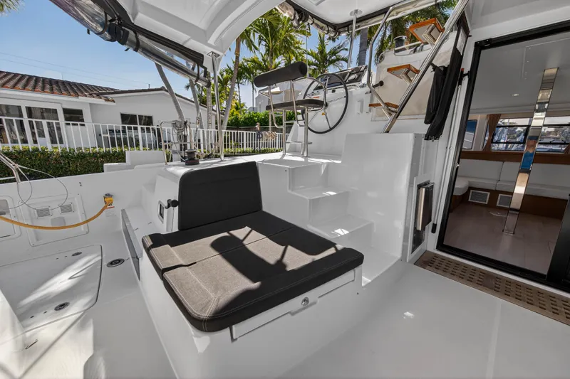 Slide: The Image of 2019 Lagoon 42 yacht cockpit with seating, steering wheel, and open cabin door. - 21
