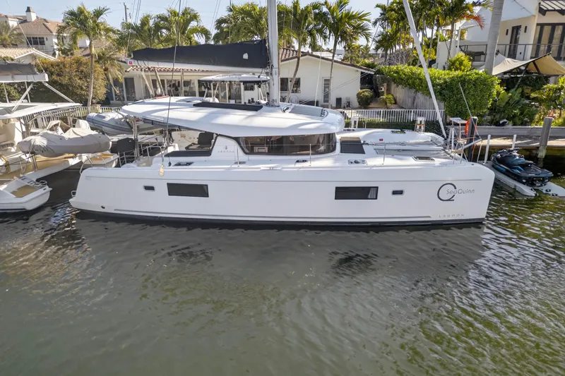 Slide: The Image of 2019 Lagoon 42 catamaran docked near palm trees and waterfront homes. - 3