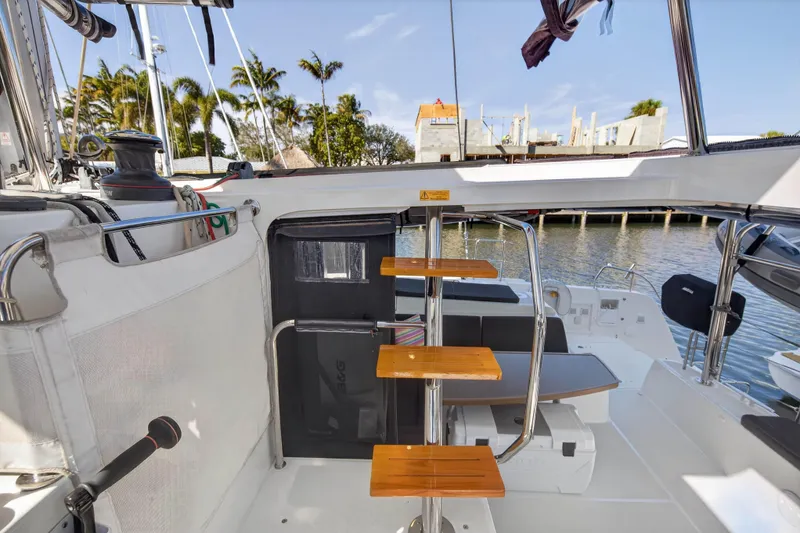 Slide: The Image of 2019 Lagoon 42 catamaran interior with wooden steps, docked near palm trees. - 34