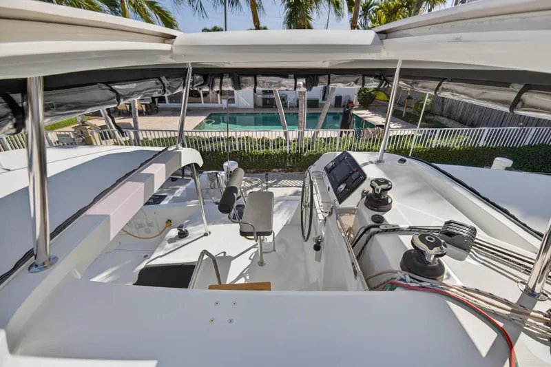 Slide: The Image of 2019 Lagoon 42 catamaran helm with modern controls, overlooking a pool and palm trees. - 35