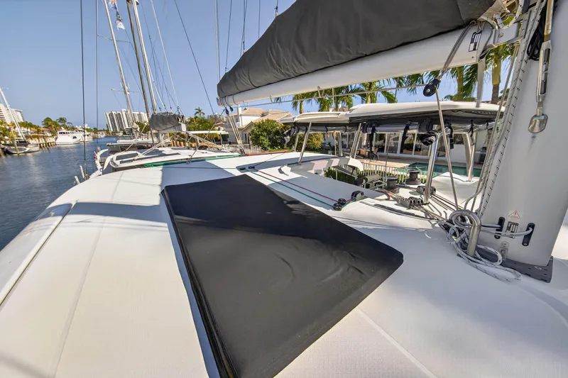 Slide: The Image of 2019 Lagoon 42 catamaran deck with sails, docked in a sunny marina. - 37