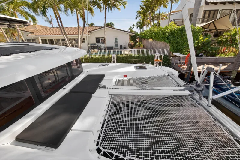 Slide: The Image of 2019 Lagoon 42 catamaran with netted deck, docked near tropical house. - 52
