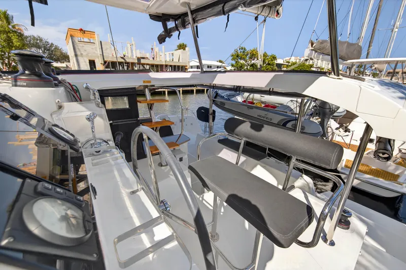 Slide: The Image of 2019 Lagoon 42 catamaran cockpit with modern seating and steering wheel, docked at marina. - 54