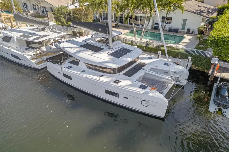 Slide: The Image of 2019 Lagoon 42 catamaran docked by waterfront home with pool and palm trees. - 7