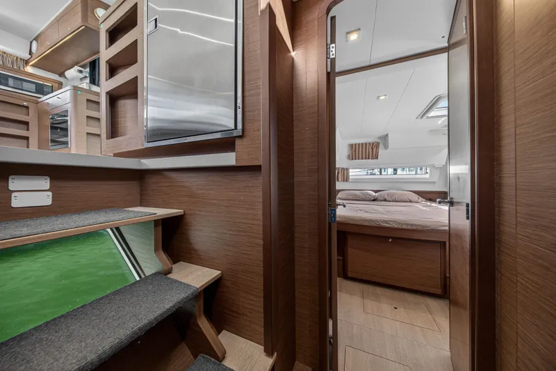 Slide: The Image of Interior of 2019 Lagoon 42 catamaran, featuring a cozy bedroom and modern kitchen area. - 92