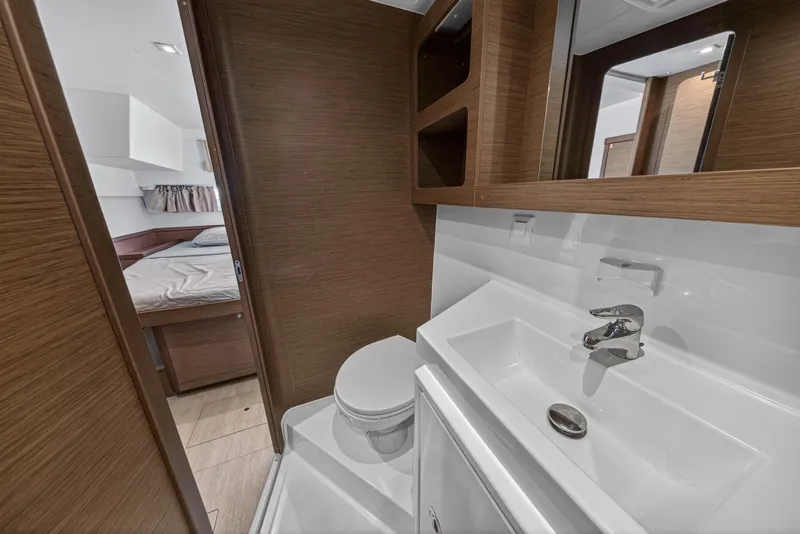 Slide: The Image of 2019 Lagoon 42 yacht bathroom with modern sink, toilet, and wooden cabinetry. - 96
