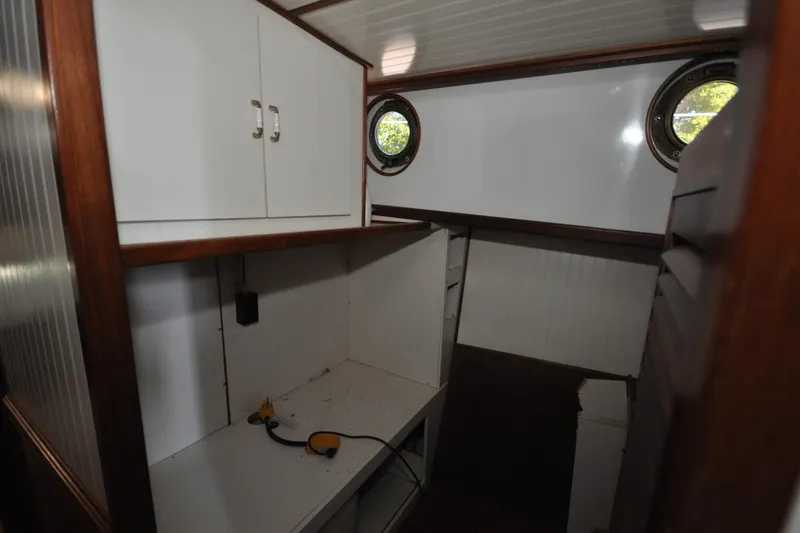 Slide: The Image of Interior of 1982 Custom Virpack Steelhull boat with white cabinets and porthole windows. - 10