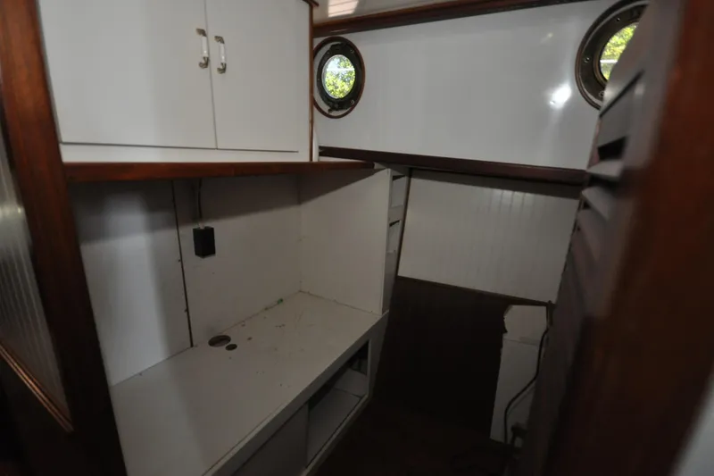 Slide: The Image of Interior of 1982 Custom Virpack Steelhull boat with white cabinets and porthole windows. - 11