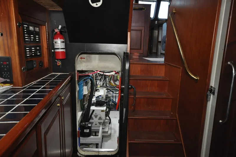 Slide: The Image of Interior of 1982 Custom Virpack Steelhull boat, featuring engine room access and wooden cabinetry. - 18