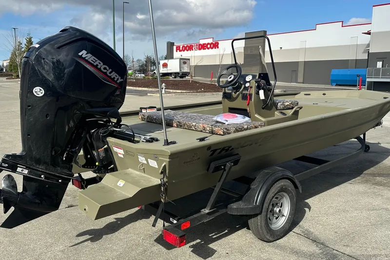 Slide: The Image of 2026 Tracker Grizzly 1860 CC boat with Mercury engine, parked outdoors near a store. - 11