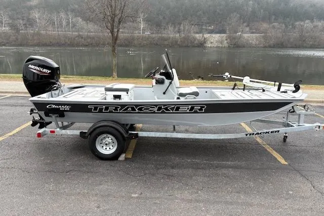 Slide: The Image of 2026 Tracker Bass Tracker Classic CC boat on trailer by a river. - 2