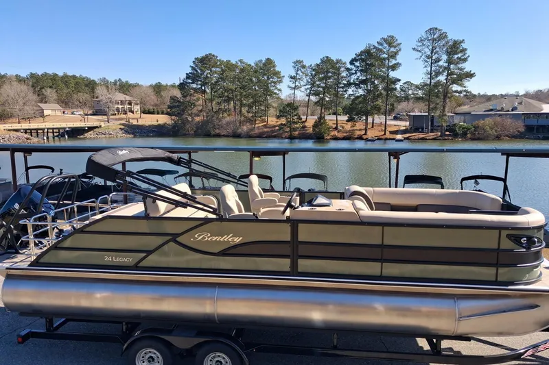Slide: The Image of 2026 Bentley Pontoons Legacy 240 Swingback on trailer by a scenic lake. - 2