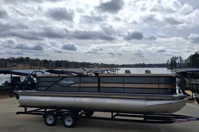 Slide: The Image of 2026 Bentley Pontoons Legacy 240 DL Navigator on trailer by a scenic lake. - 4