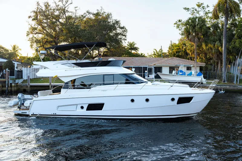 Slide: The Image of 2013 Bavaria Virtess 420 Fly yacht cruising on a serene waterway, surrounded by lush greenery. - 4