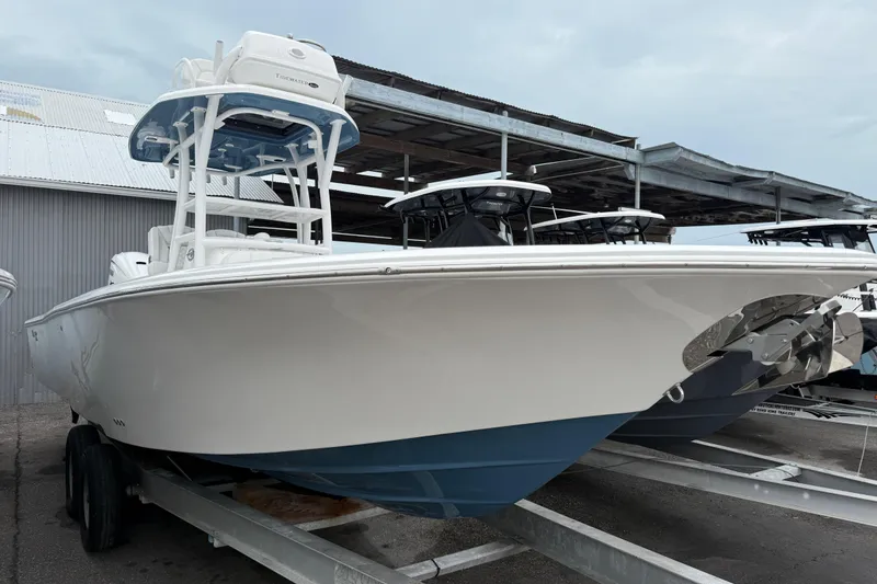 Slide: The Image of 2026 Tidewater 2700 Carolina Bay boat on trailer, white hull, blue bottom, docked outdoors. - 3