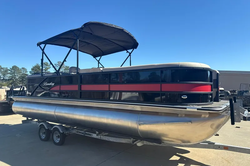 Slide: The Image of 2026 Bentley Pontoons Legacy 243 Navigator on trailer, black and red design, sunny day. - 4
