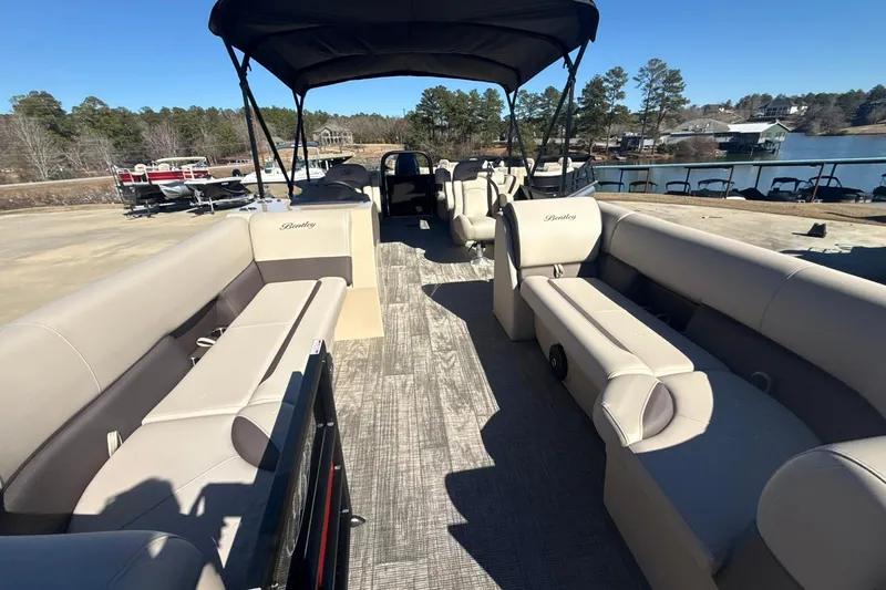 Slide: The Image of 2026 Bentley Pontoons Legacy 243 Navigator with spacious seating and canopy, docked by a serene lake. - 6