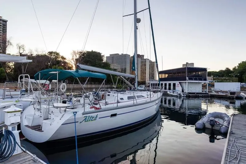 Slide: The Image of 1999 Catalina 400 sailboat docked at marina, surrounded by calm water and urban skyline. - 4