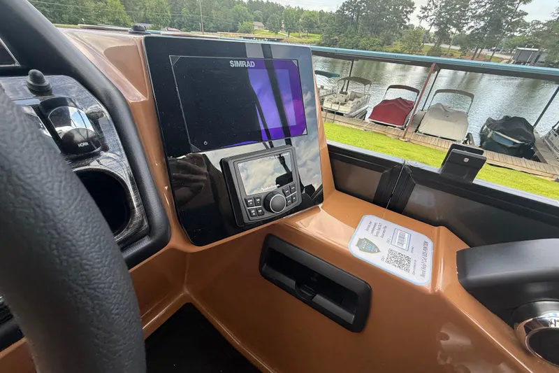 Slide: The Image of 2026 Bentley Pontoons Elite 253 Admiral dashboard with Simrad display, overlooking docked boats. - 4