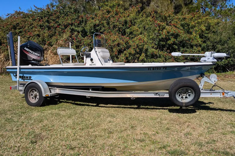 Slide: The Image of 2015 Mako 18 LTS boat on trailer with Mercury engine, parked on grass. - 3