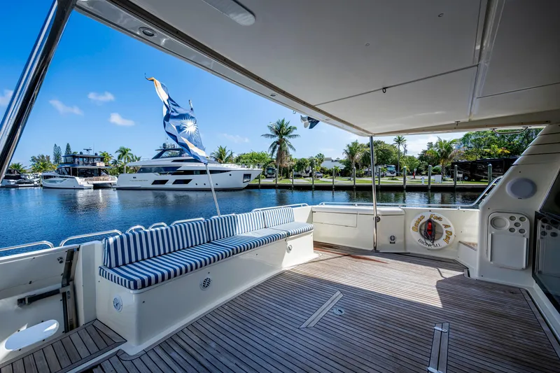 Slide: The Image of 1997 Ferretti Yachts 650 deck with striped seating, docked by palm trees and water. - 11