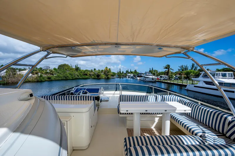 Slide: The Image of Luxurious 1997 Ferretti Yachts 650 with striped seating, cruising on a scenic waterway. - 13