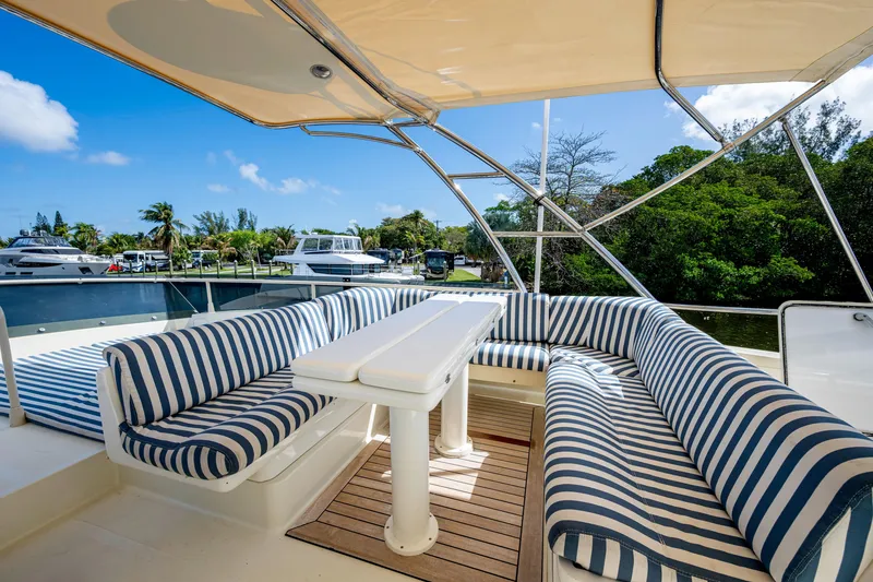 Slide: The Image of Luxurious 1997 Ferretti Yachts 650 with striped seating on deck, docked by lush greenery. - 15