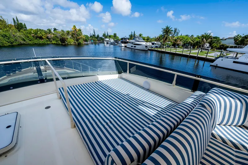 Slide: The Image of Luxurious 1997 Ferretti Yachts 650 with striped sunbed, docked by a scenic waterfront. - 17