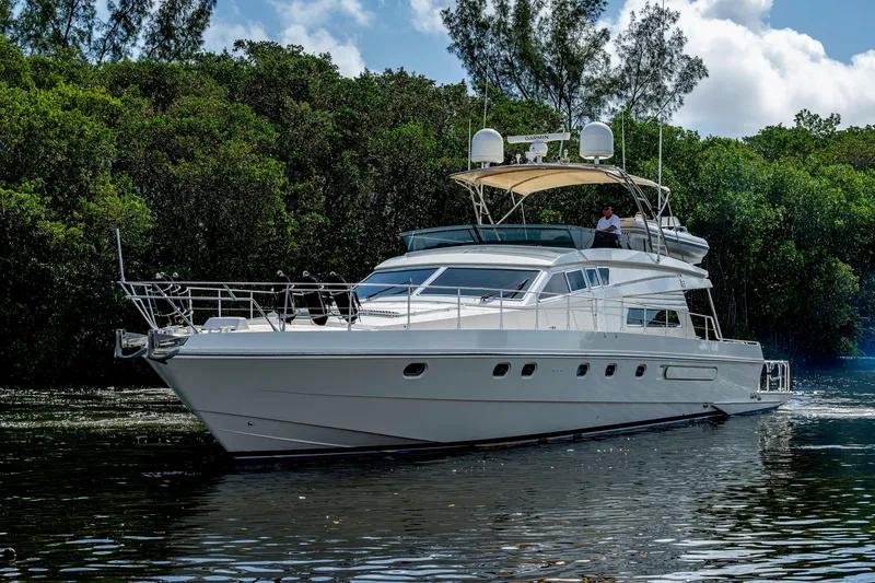 Slide: The Image of 1997 Ferretti Yachts 650 cruising on a serene waterway, surrounded by lush greenery. - 4