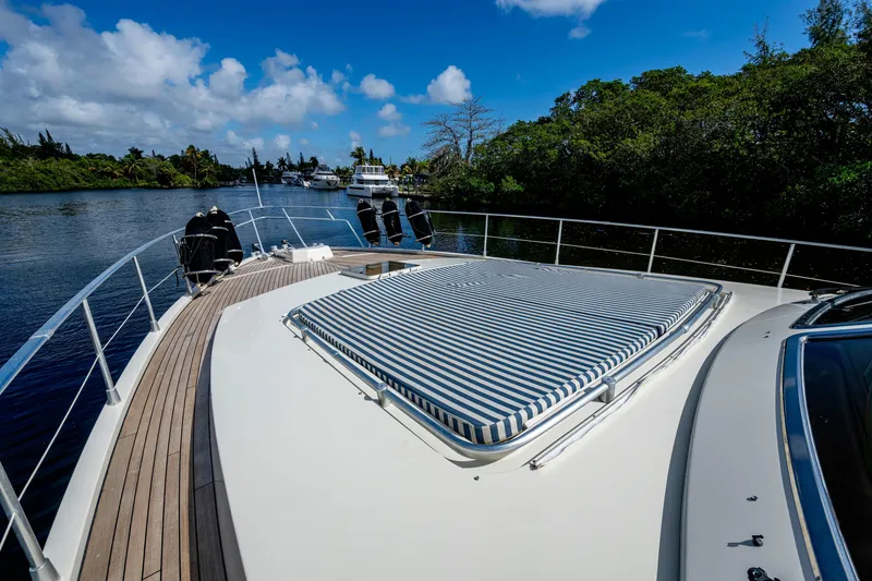 Slide: The Image of 1997 Ferretti Yachts 650 on serene waterway, featuring striped sunpad and lush greenery. - 8