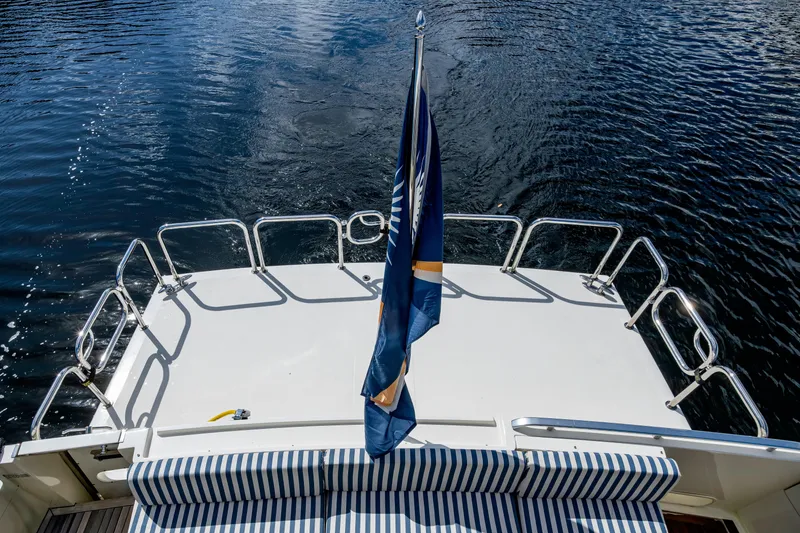 Slide: The Image of Aft deck of 1997 Ferretti Yachts 650 with striped seating and flag, overlooking water. - 9