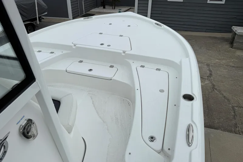Slide: The Image of 2026 Tidewater 2210 Carolina Bay boat deck with storage compartments, docked outdoors. - 8