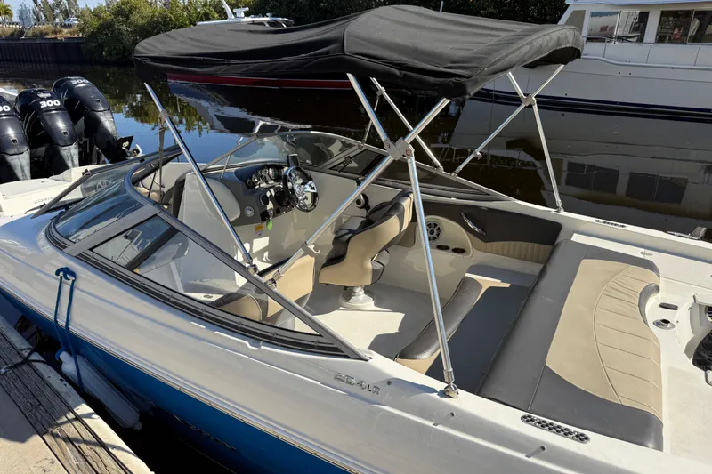 The Image of 2018 Stingray 204 LR boat with canopy, docked by the water. - 0
