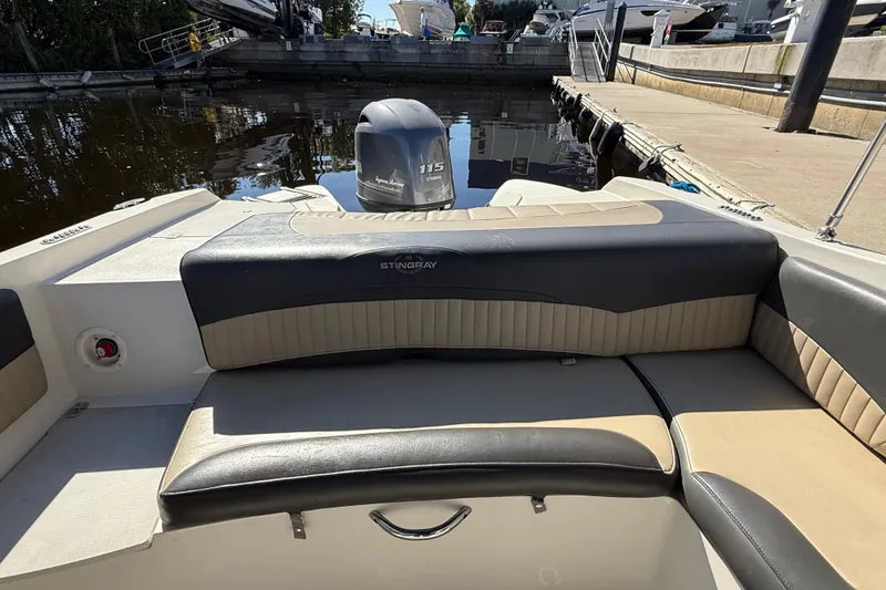 Slide: The Image of 2018 Stingray 204 LR boat interior with seating and outboard motor at dock. - 12