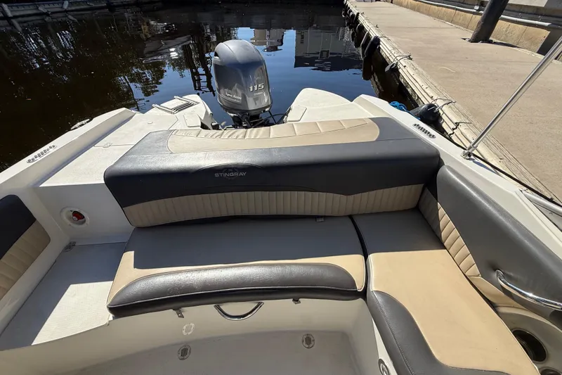 Slide: The Image of 2018 Stingray 204 LR boat interior with seating and outboard motor at dock. - 13